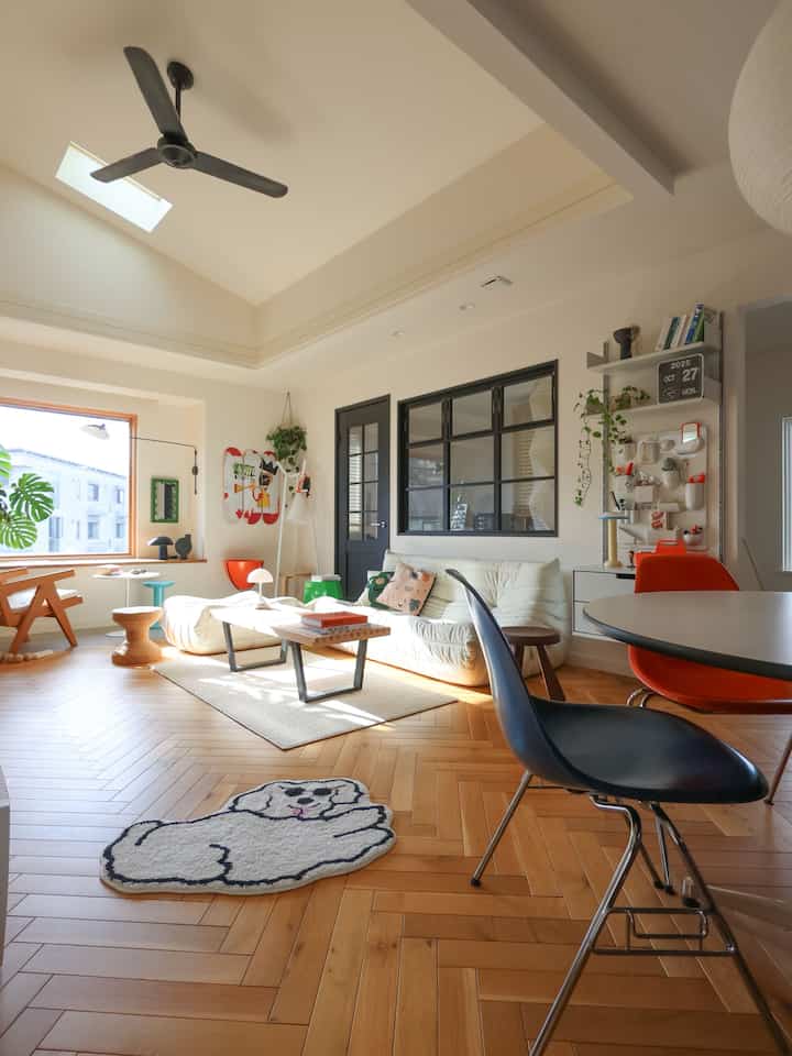 ウッドトーンとホワイトが調和するミッドセンチュリーモダンのリビング、ソファと丸いダイニングテーブルが配置された明るく居心地の良い空間