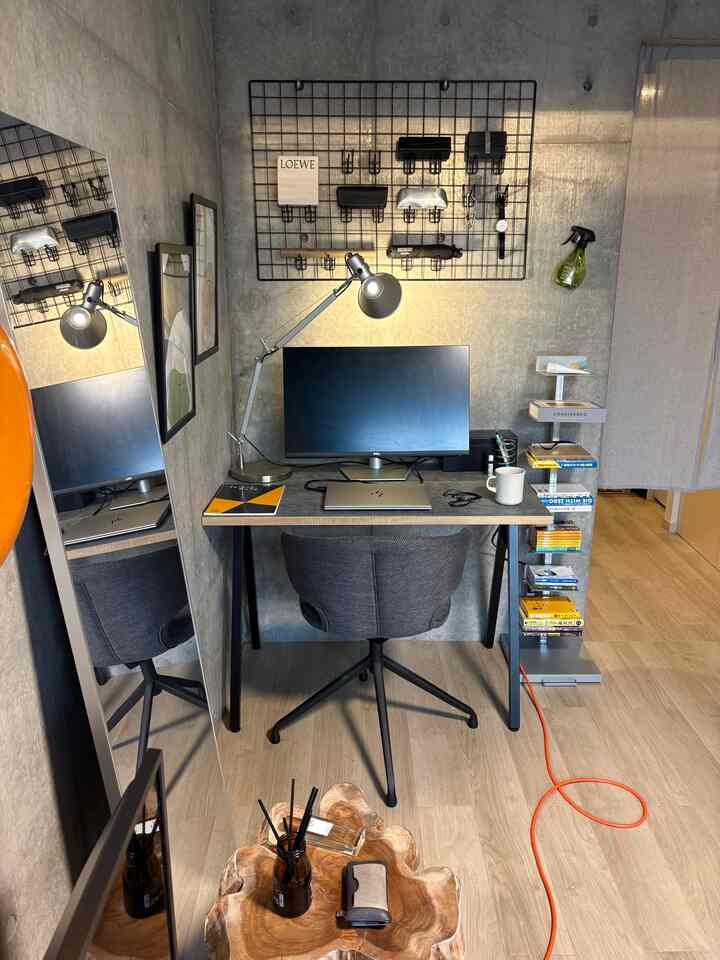Natural-toned 1K home office featuring concrete wall, work desk, and swivel office chair in a modern atmosphere