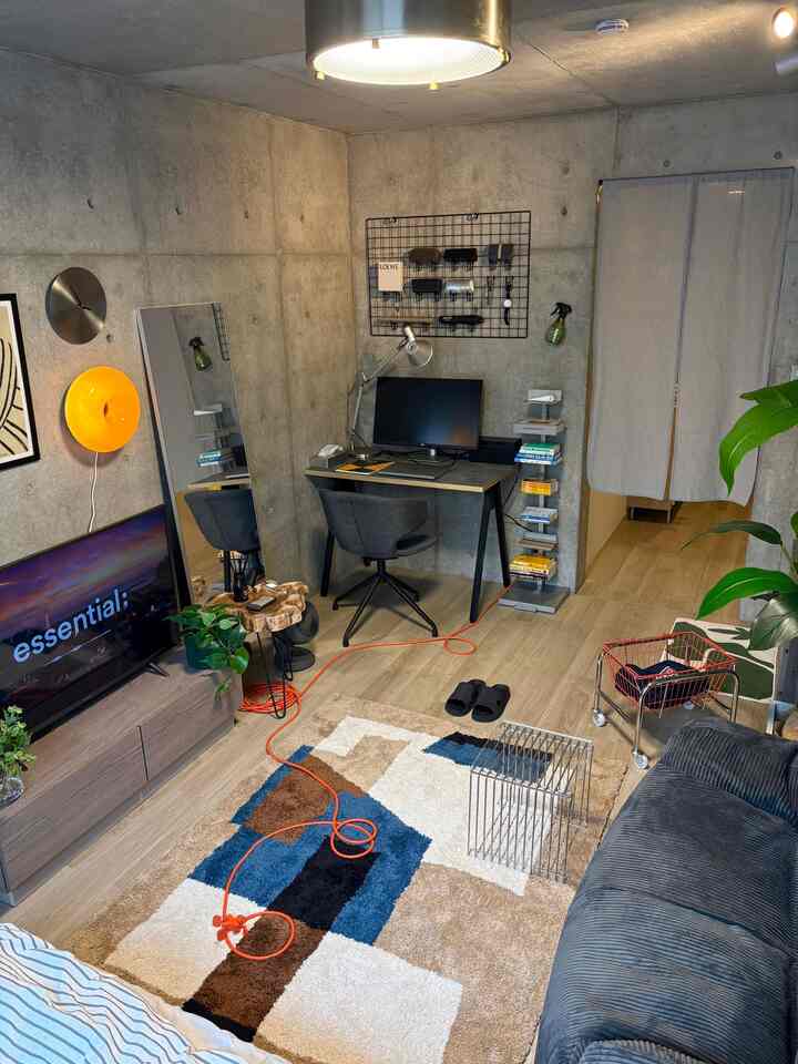 Natural wood-tone flooring and concrete walls in a single household living room with home office setup