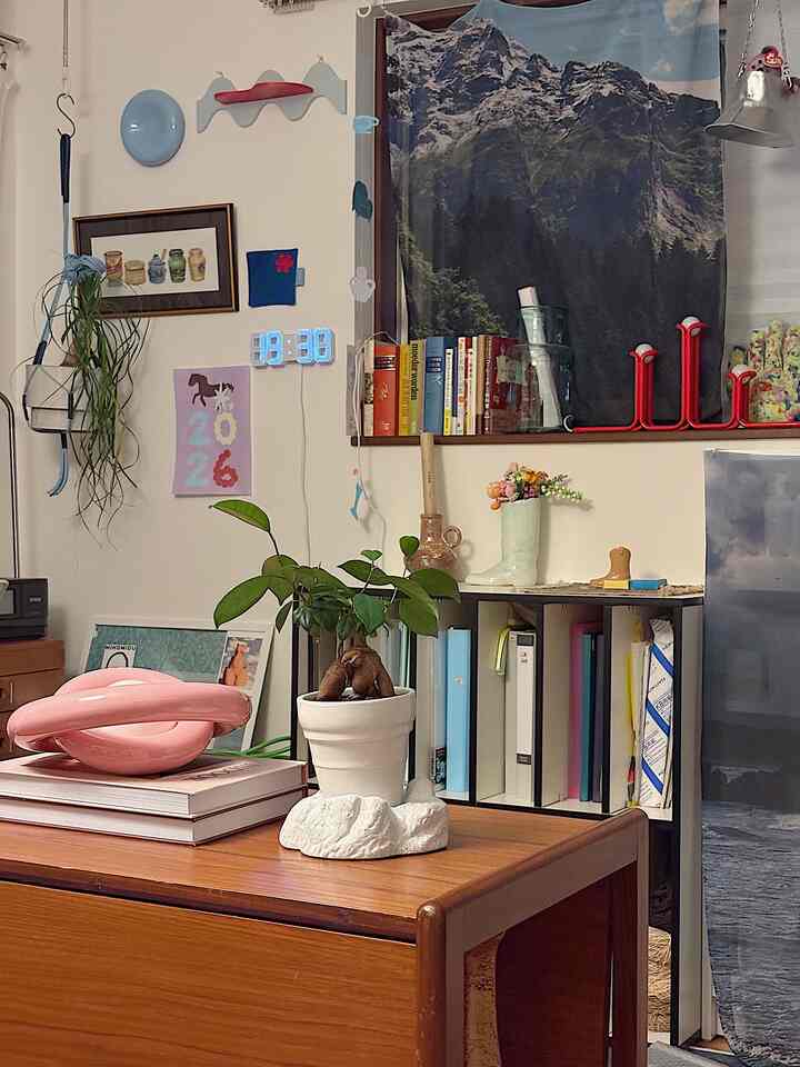 白い背景と木目調の家具が調和するホームオフィス、本棚とデスクに植物が配置された雰囲気のある空間