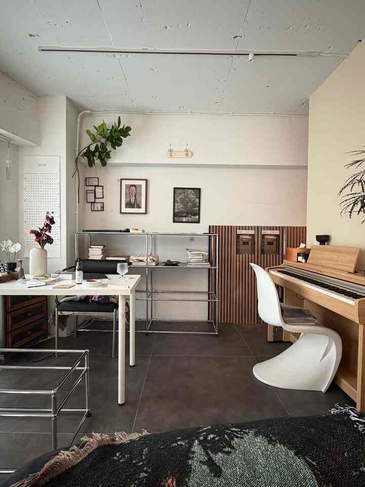 Natural tone modern living room and study space featuring a piano and desk with clean, minimal design