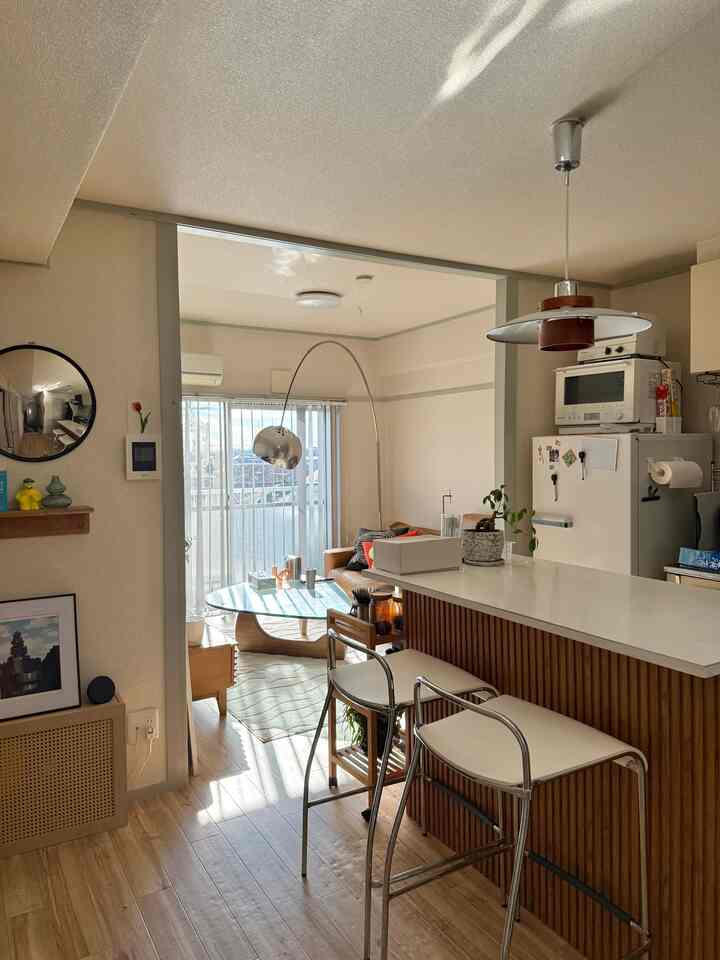 Warm natural-toned 2LDK living and kitchen space featuring wood flooring and Arco lamp, creating cozy atmosphere