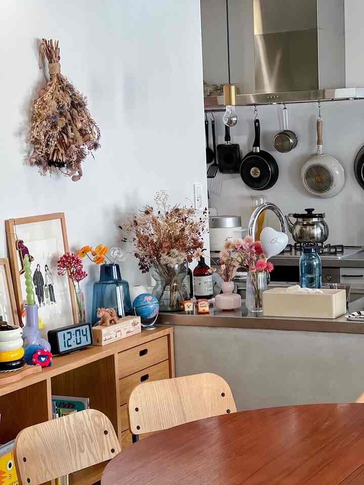 ナチュラルな色調の小さなキッチンとダイニングエリア、ドライフラワーと調理器具が配置された温かみのある空間