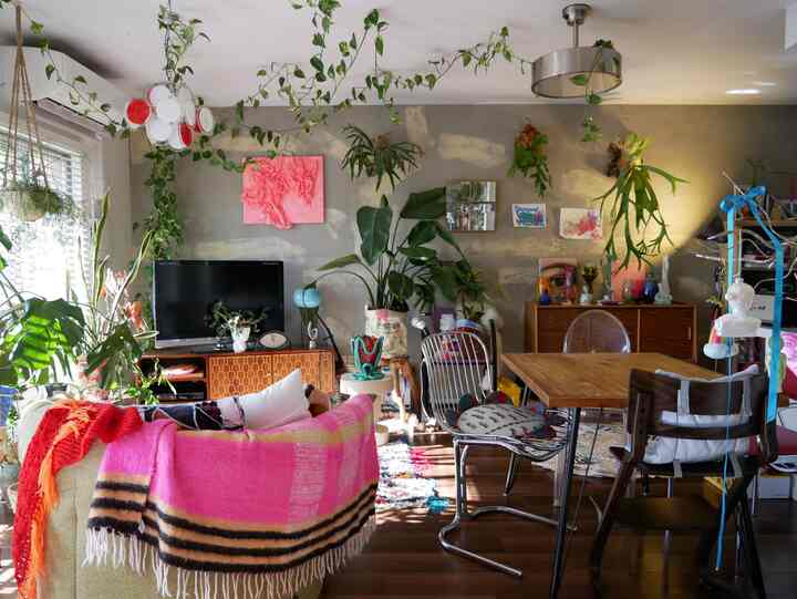 Gray-toned wall living room featuring wooden dining table, various plants, and a sofa blending natural and modern styles