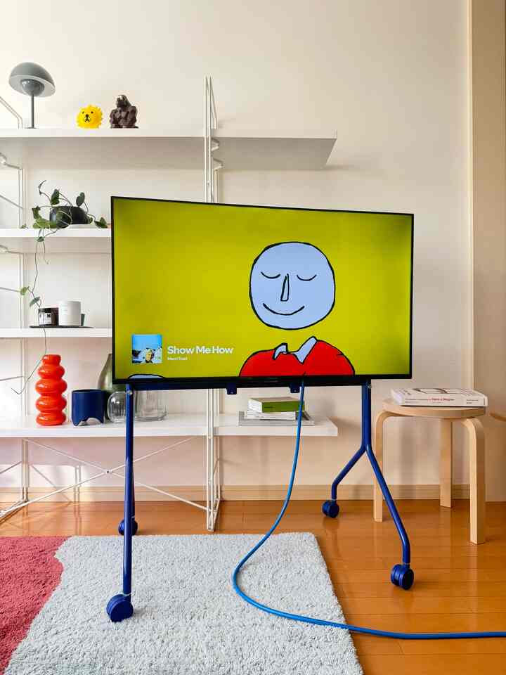 ホワイトとウッドトーン、ブルーのアクセントがあるミッドセンチュリーモダンのリビング、テレビ台や棚、ラグが配置された印象的な空間