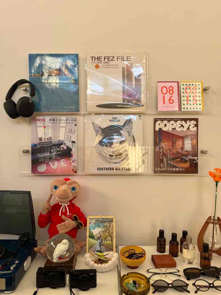 明るく透明なアクリル製の壁掛け棚にレコードと雑誌が飾られたミッドセンチュリーモダンなインテリア