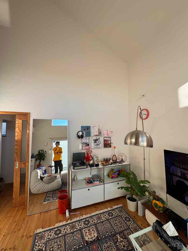 白と木目調の調和がとれたリビング、大型の鏡とメタルシェルフが配置されたナチュラルモダンなインテリア