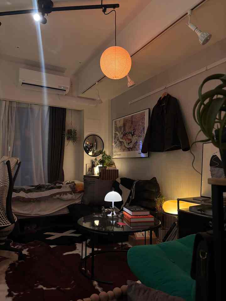 Warmly lit 8-tatami studio living room featuring wood and black furniture, pendant light, and indirect lighting creating a cozy atmosphere