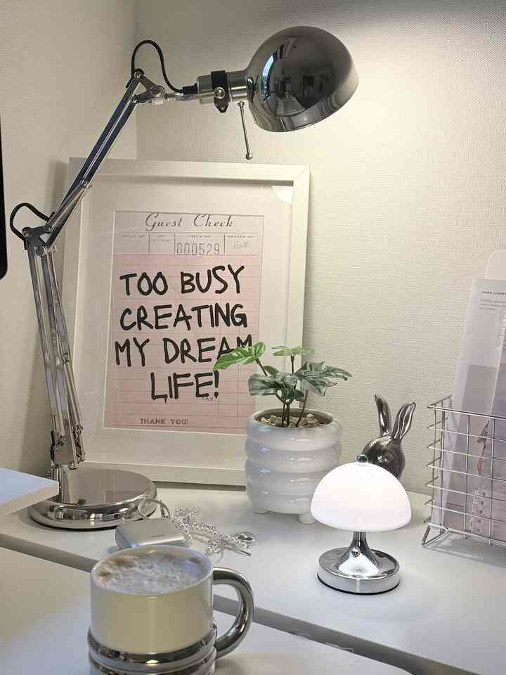 シルバーとホワイトの色調のホームオフィスデスク、2つのメタリックランプと植物が配置された雰囲気のある作業空間