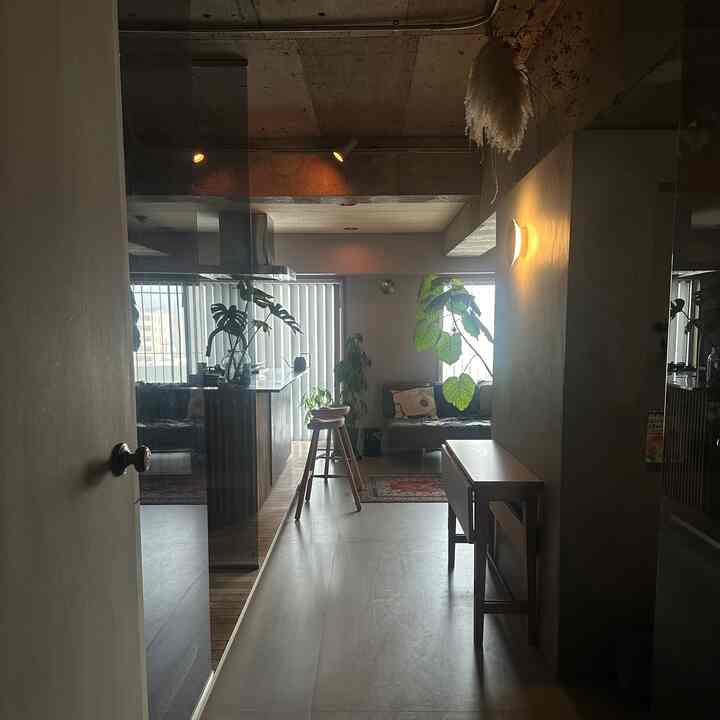 ナチュラルトーンのリビング、3人掛けソファとコンソールテーブル、スツール、観葉植物が配置されたモダンなインテリア