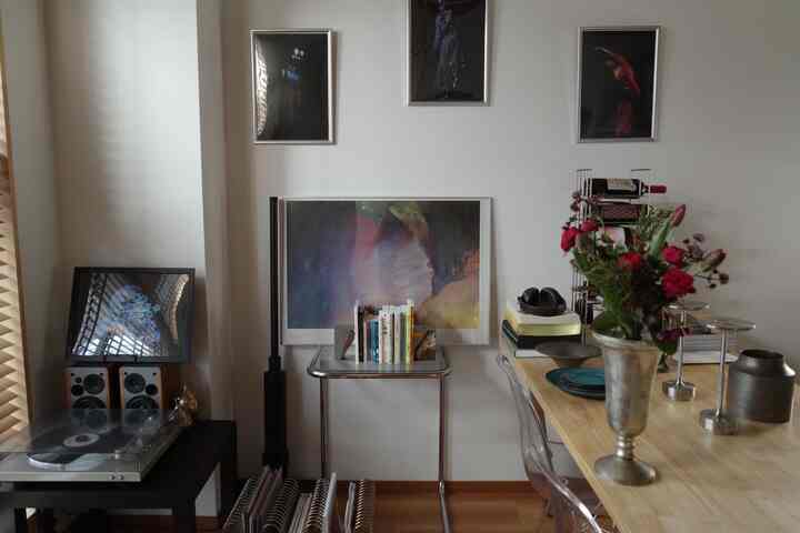 白い壁とナチュラルカラーの床、ミッドセンチュリーモダン家具とワインラック、花瓶が配置された一人暮らしの1LDKリビングの印象的な空間