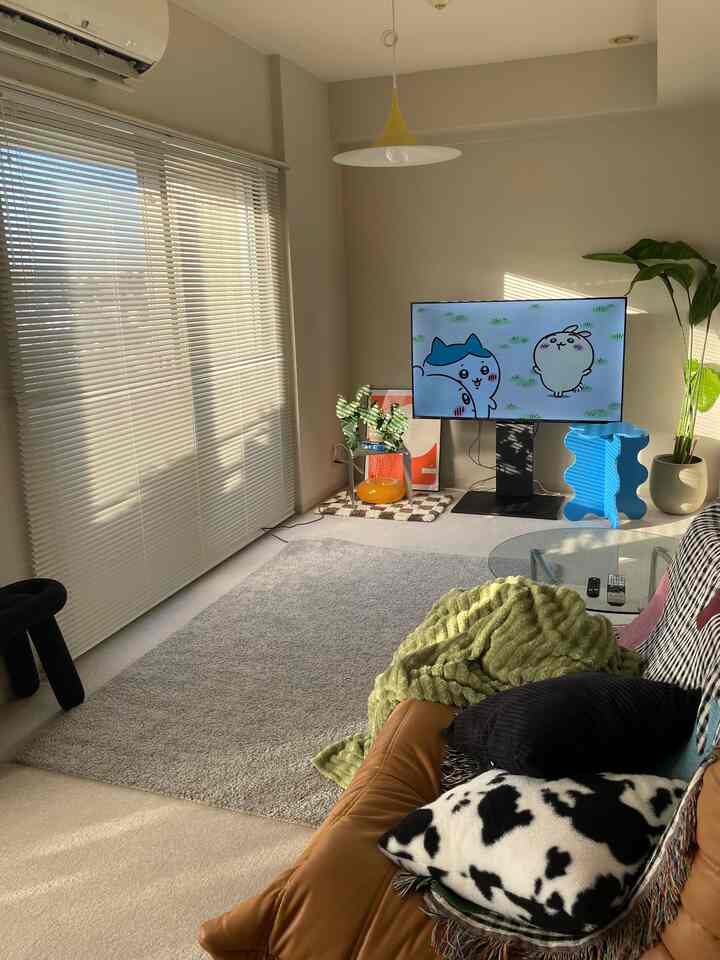 白と茶色のトーンのリビング、ソファとラグ、子供用家具が配置された落ち着いた雰囲気の空間