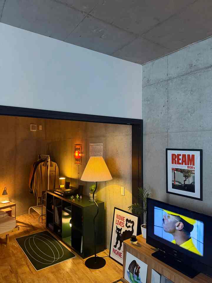 Modern studio living room in black and wood tones, featuring a floor lamp and framed artworks creating a warm cozy atmosphere