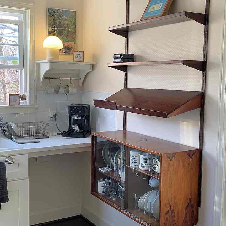 ナチュラルな木製の壁棚と白いキッチン空間、コーヒーマシンとマグカップが配置された雰囲気のあるおうちカフェスタイルのキッチン