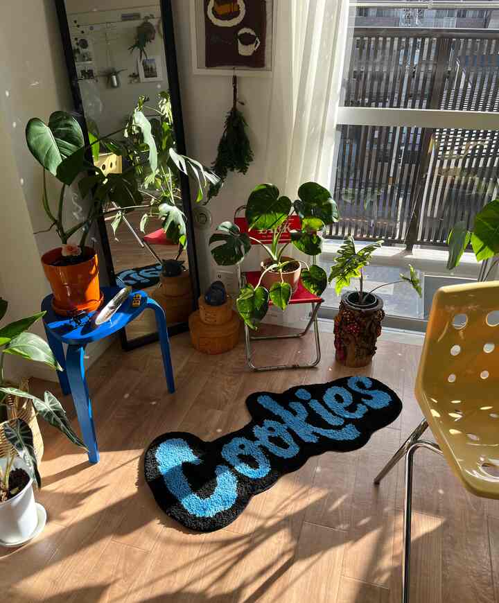Natural-toned balcony space with warm sunlight and green plants, featuring colorful chairs and a distinctive rug in a modern interior