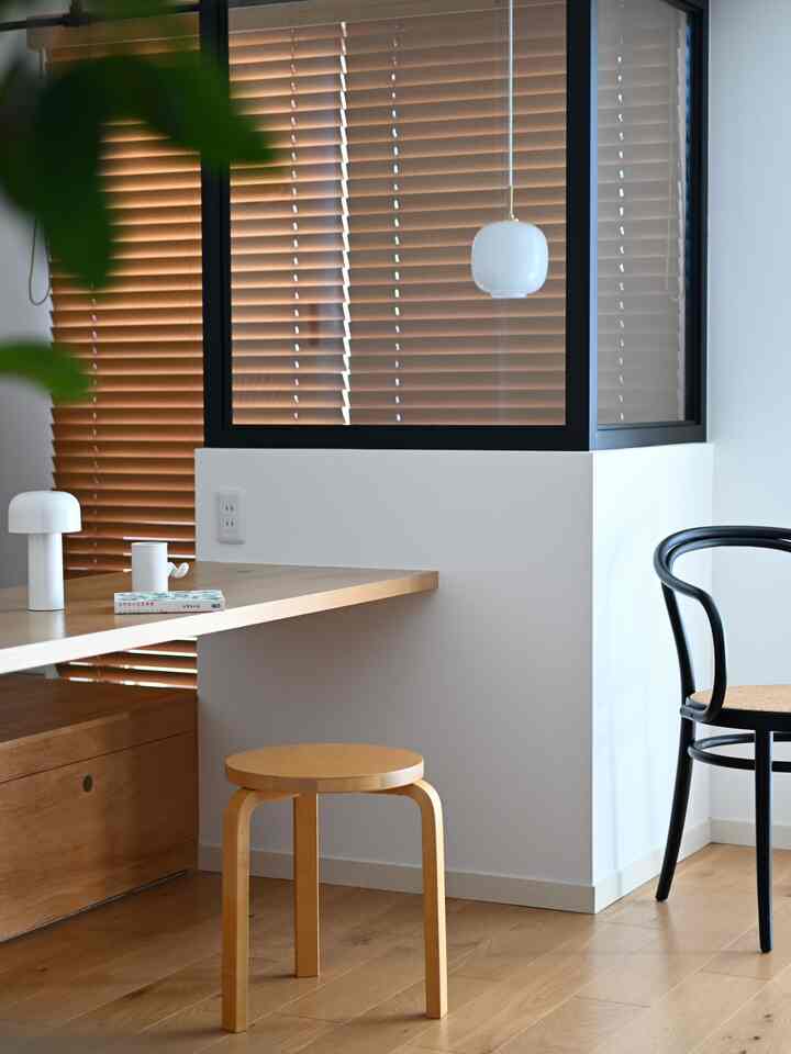 ナチュラルなブラウンの木材色とホワイトが調和したキッチン、スツールとテーブルランプが配置されたモダンなインテリア