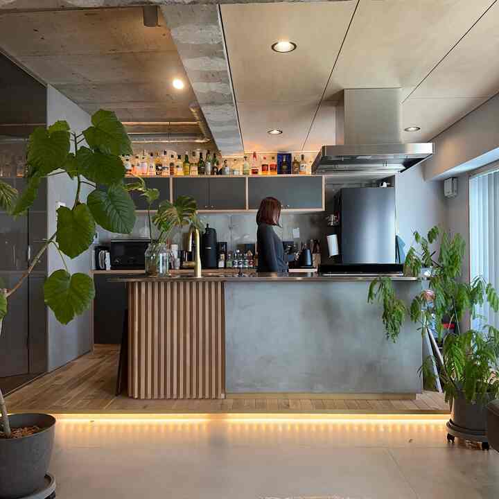 ナチュラルな色調のワンルームキッチン、ウッドトーンとコンクリート素材が調和した印象的な空間