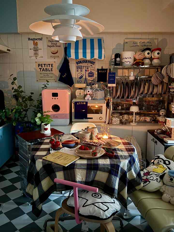 紫のチェック柄テーブルクロスが掛けられたダイニングルーム、壁にポスターとヴィンテージ風の小物が配置された雰囲気あるおうちカフェ空間