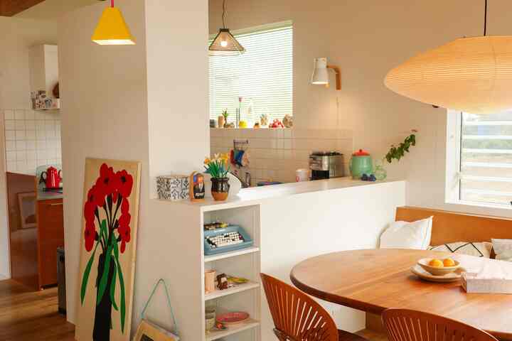 白と茶色のトーンのダイニングルーム、丸いダイニングテーブルとペンダントライトが配置された暖かく自然な印象的な空間