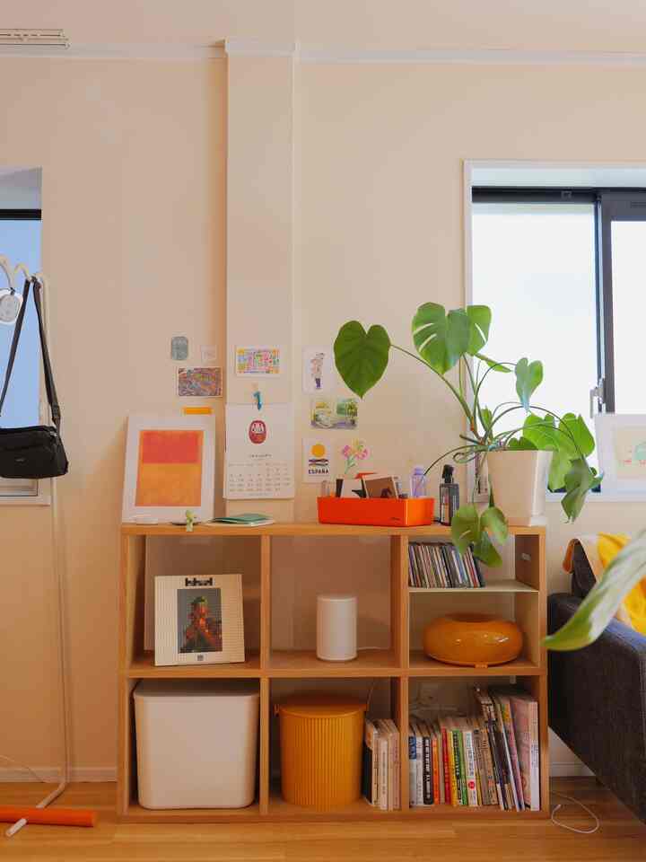 明るいベージュ色の壁とナチュラルウッドの棚、植物が配置された清潔感のあるリビング