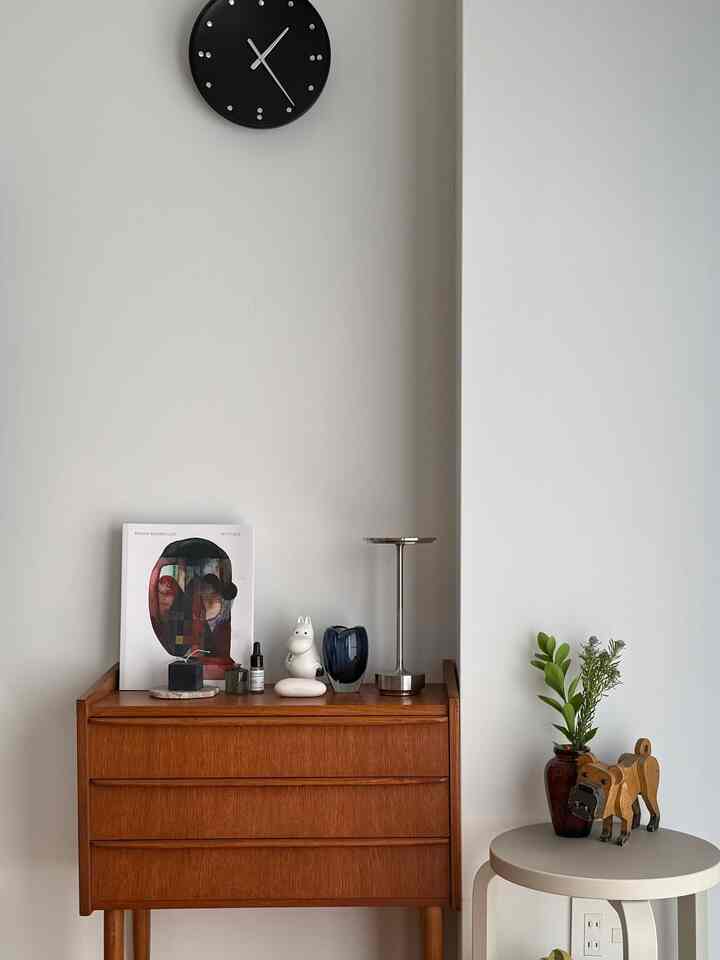 白い壁とナチュラルな木製のチェストが配置されたミニマルで北欧ヴィンテージなインテリア