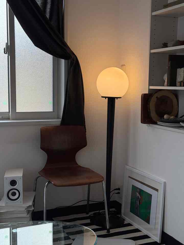 ナチュラルカラーのミッドセンチュリーモダンなコーナー、ヴィンテージ風のフロアランプと木製チェアが配置された雰囲気のある空間