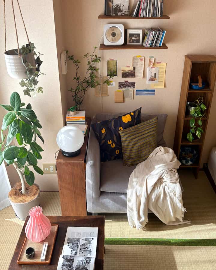 ナチュラルなベージュトーンのワンルームリビング、グレーのソファと木製のダイニングテーブル、植物が配置された雰囲気のあるインテリア