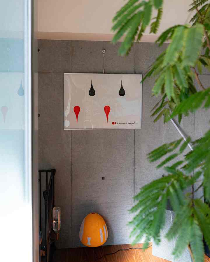 Mid-century modern space next to the kitchen featuring an exposed concrete wall with Isamu Noguchi wall art, an orange Akari floor lamp, wooden floor, and green plants