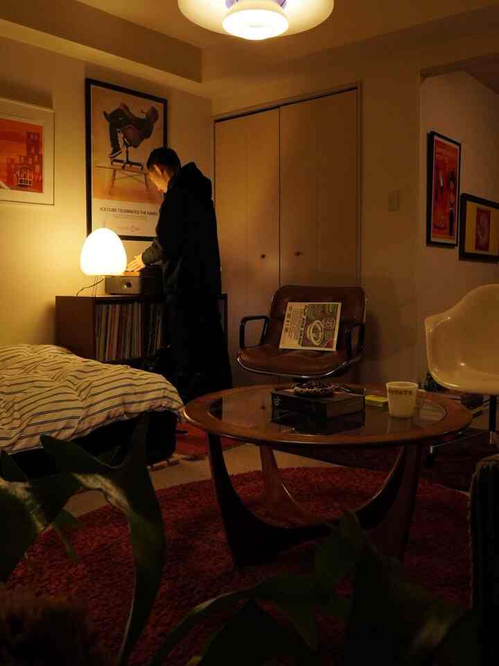 Warmly lit Mid-Century Modern studio apartment featuring a record player, coffee table, and cozy ambiance