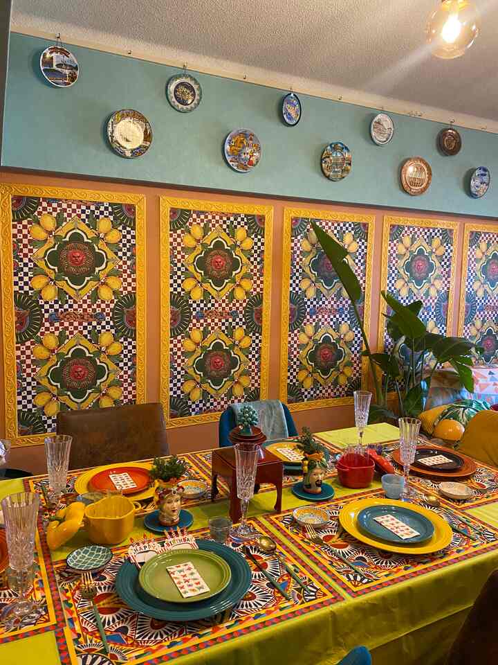 黄色と緑の色調のダイニング、鮮やかな壁飾りと多彩な食器が配置された雰囲気あるインテリア