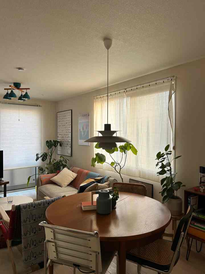 ライトブラウン調のミッドセンチュリーモダンなリビングダイニング、ソファと丸いダイニングテーブル、植物が配置された雰囲気のあるインテリア