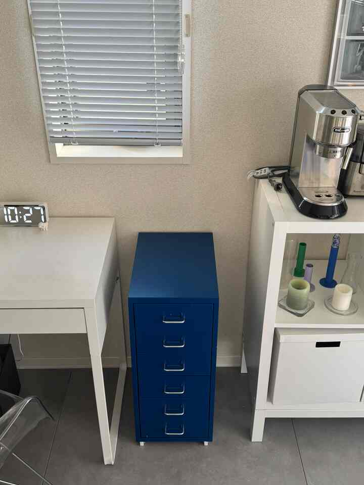 白と青の色調が特徴のキッチンスペース、コーヒーマシンと収納棚が配置されたシンプルなインテリア