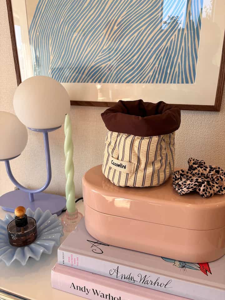 Cozy interior space featuring blue striped wall art above a pink and brown toned small table adorned with various decorative items