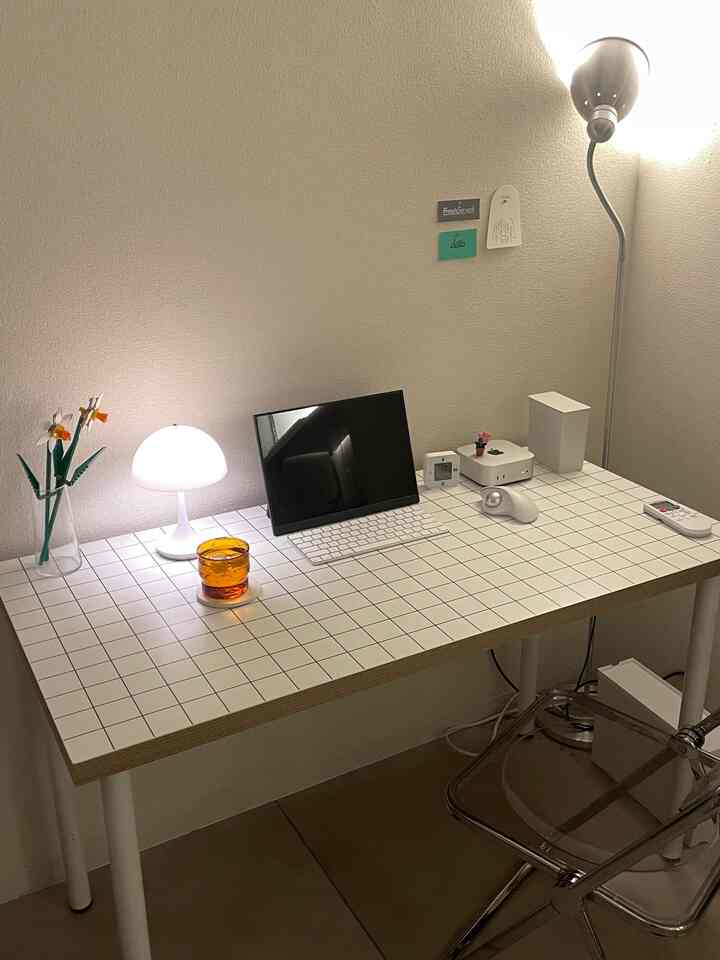 Modern home office for a single household featuring a white tiled desk and transparent chair in a compact space