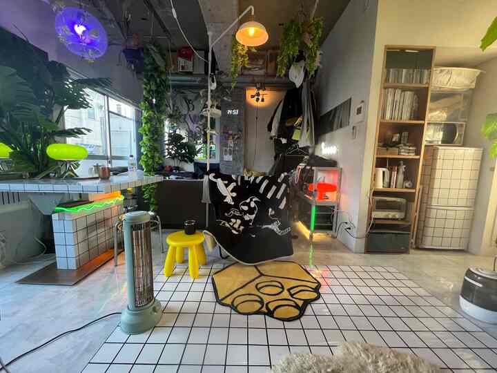 白と緑のトーンが調和したワンルーム、黄色のスツールとスローが配置された雰囲気のあるインテリア