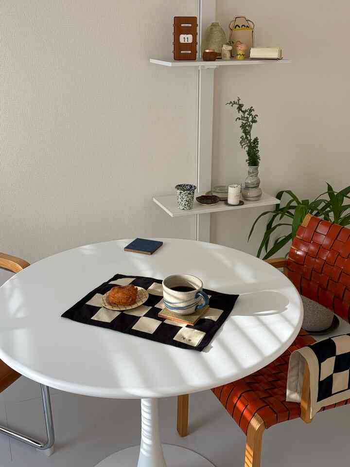 白と茶色のトーンのダイニングルーム、丸いテーブルとレザーの椅子が配置された雰囲気のあるインテリア