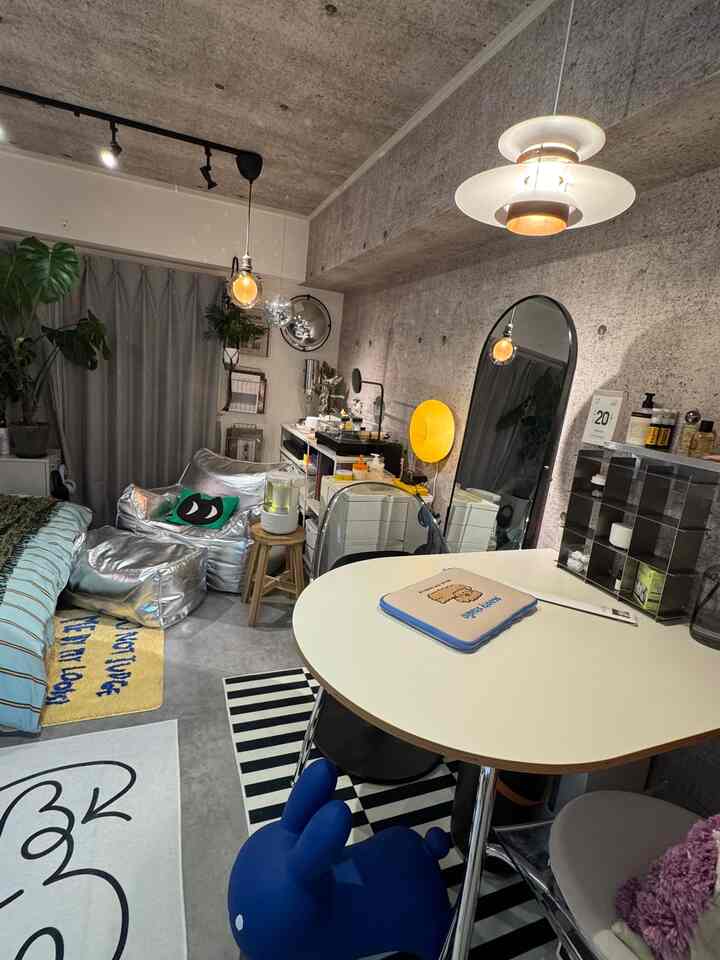 Modern 1K kitchen-living space with exposed concrete walls and silver bean bag sofa