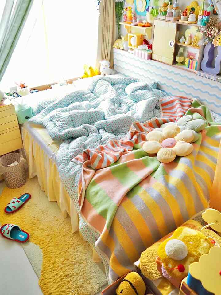 明るい黄色とナチュラルカラーの子供部屋、ぬいぐるみやブランケットが温かみのある雰囲気で配置された空間