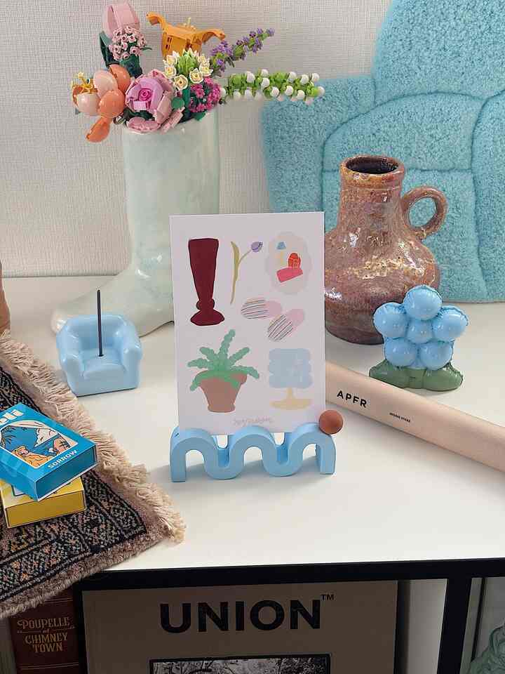 ブルートーンの落ち着いたインテリア空間、中央に花瓶とポストカードなど多彩な装飾品が配置されたテーブル