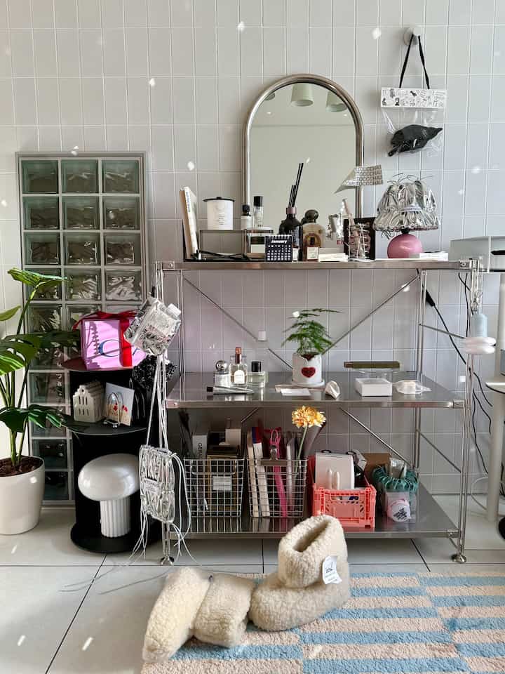 明るくナチュラルな色調のリビング、ステンレスの棚とアールデコ風の鏡が配置された印象的なインテリア