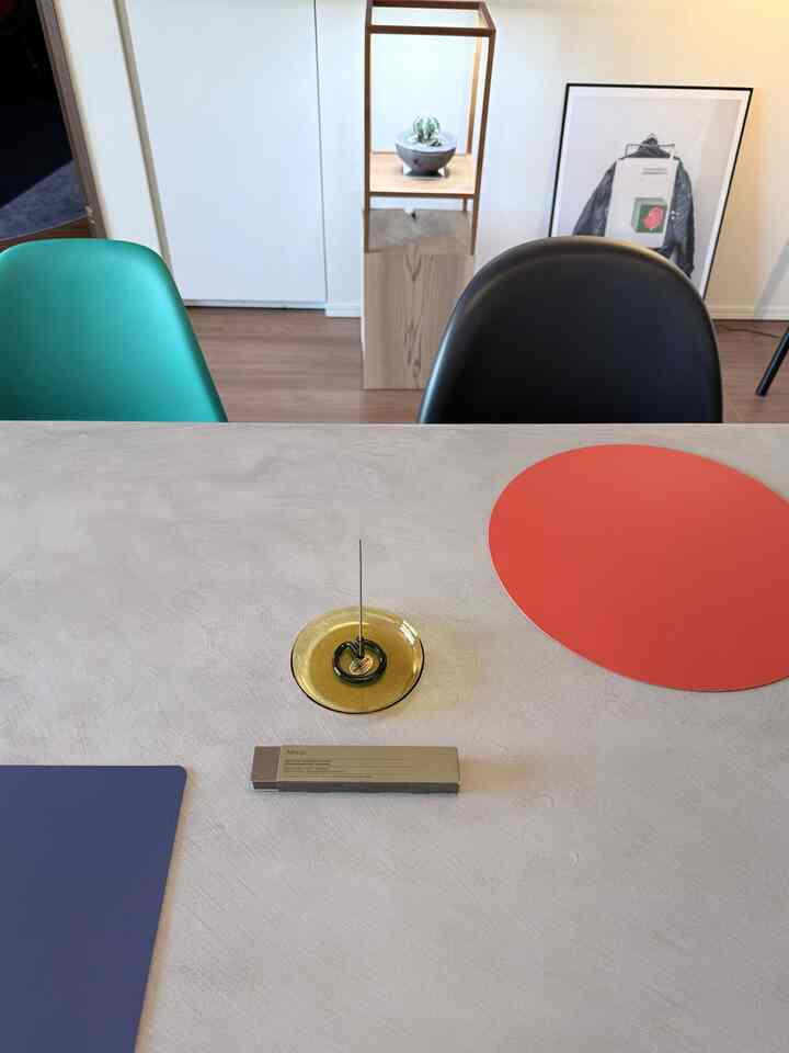 Modern, simple living room dining table featuring an incense holder and colorful placemats arranged on the surface