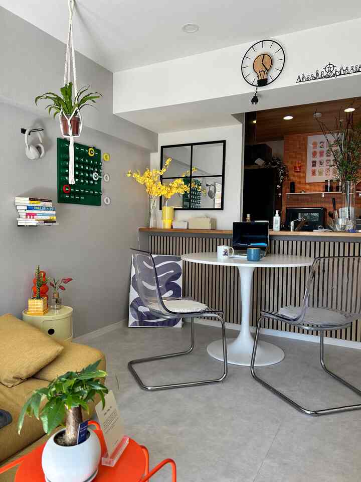 白とグレーの色調のダイニングルーム、透明な椅子と丸いダイニングテーブルが配置されたミッドセンチュリーモダンの雰囲気あるインテリア