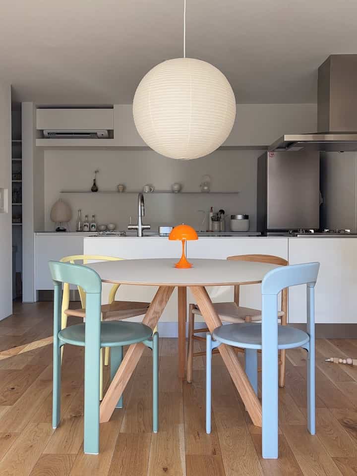 Natural color Nordic dining room featuring a round dining table with pastel dining chairs and a large pendant light, creating a clean and cozy atmosphere
