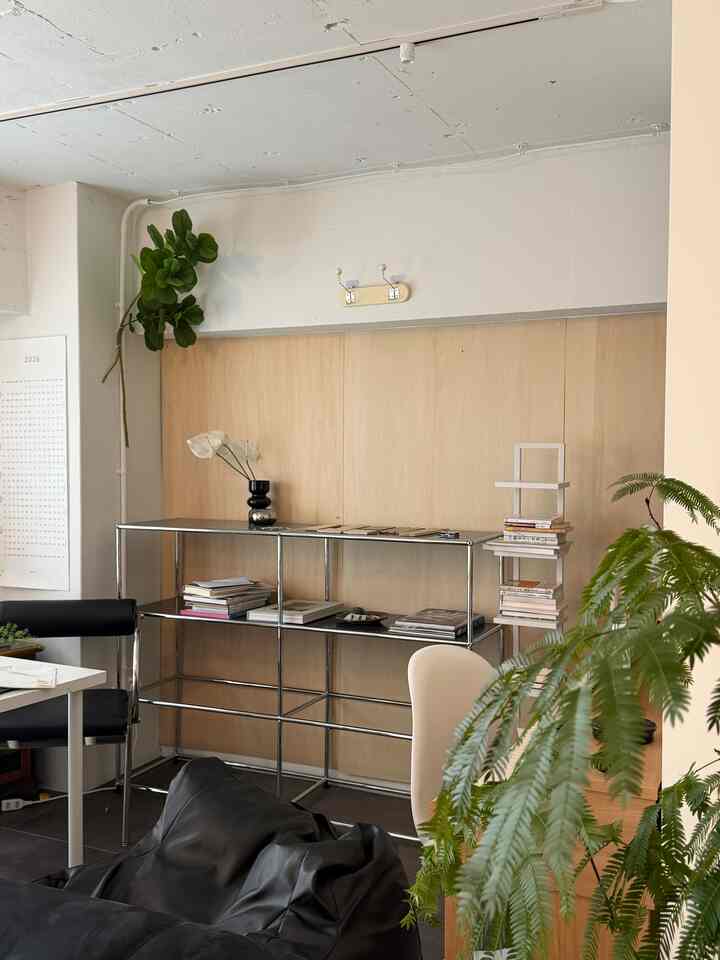 白とナチュラルウッド調のホームオフィス、メタルの棚とグリーンの植物が配置された雰囲気のあるモダンなインテリア