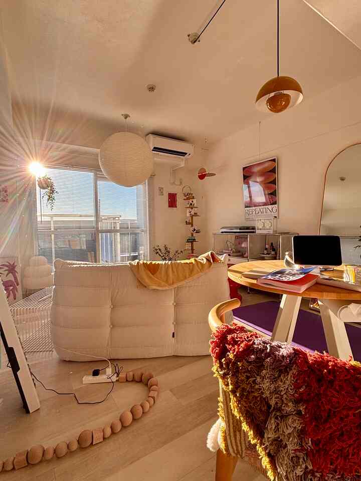Warm wood tone and white living room featuring a Togo sofa, round table, and art poster in a cozy cafe-style interior