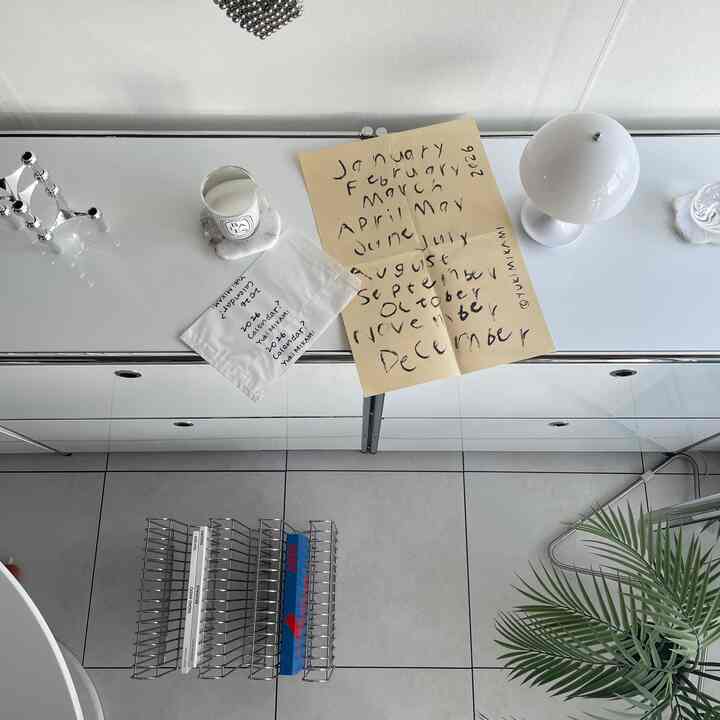 White and gray toned entrance area with minimal storage furniture, candles and a calendar arranged neatly on top, creating a clean interior