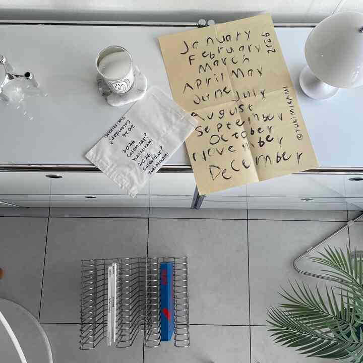 白とグレーのミニマルなホームオフィス、デスク上に2026年のカレンダーとキャンドルが配置された印象的な空間