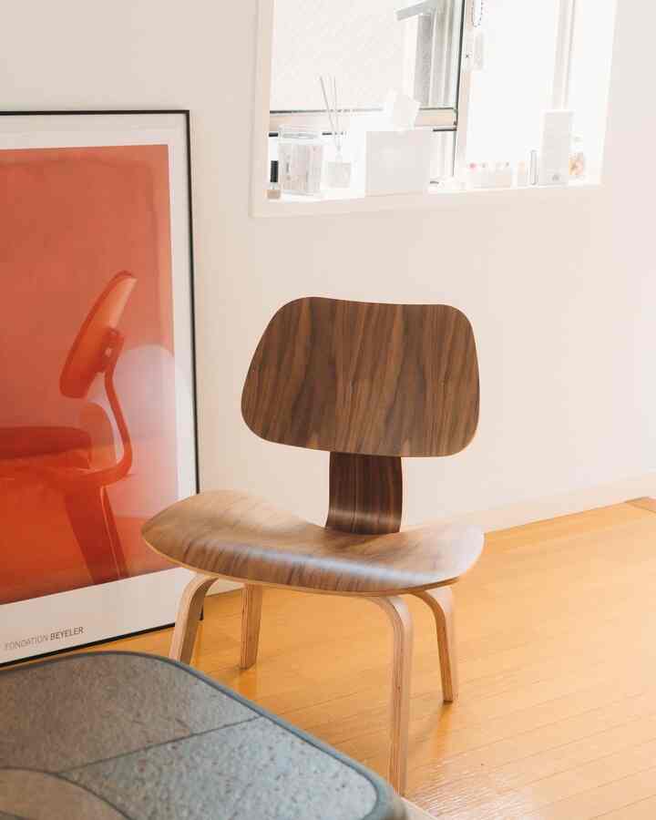 木目調と白色の玄関スペース、イームズラウンジチェアと赤いアートが配置されたミニマルなインテリア