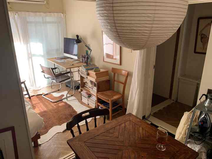 温かみのあるベージュと木目調のワンルーム、書籍とラグが配置されて雰囲気のあるホームオフィス空間