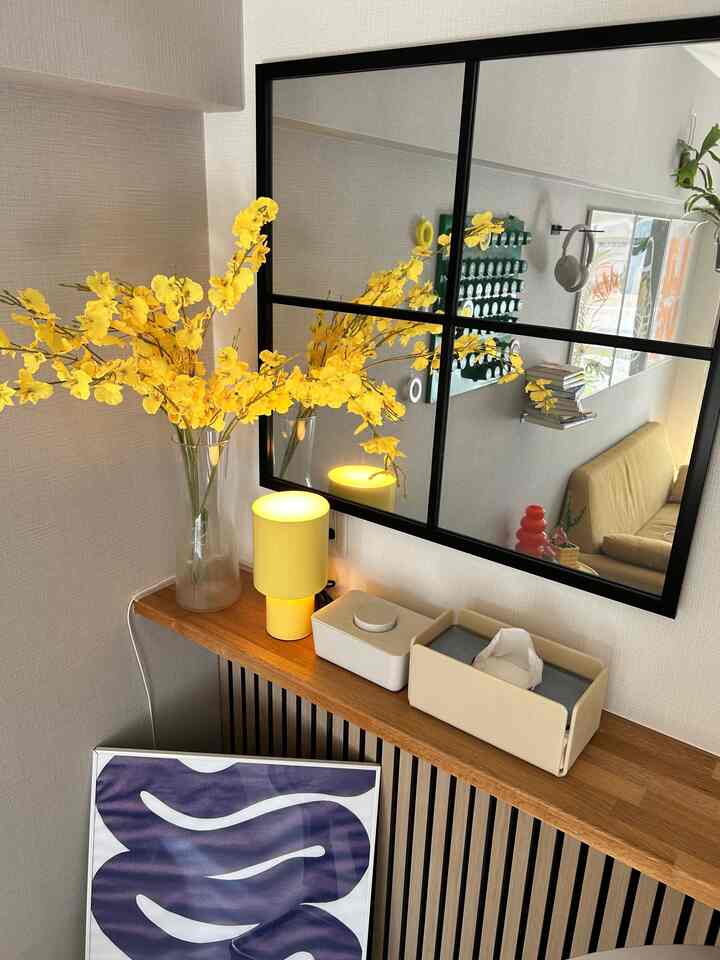Yellow flowers and lamp on wood-tone living room wall-mounted mirror space